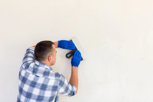 Handwerker glättet frischen Kalkputz an einer Berliner Altbauwand